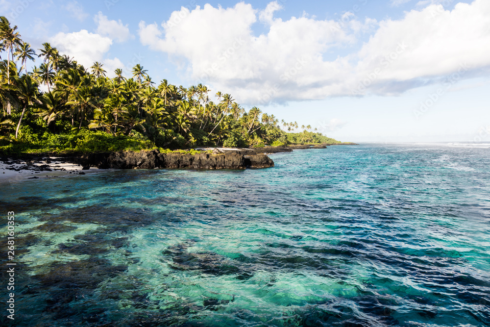 Clear turquoise water and palm trees on tropical island Samoa in Polynesia