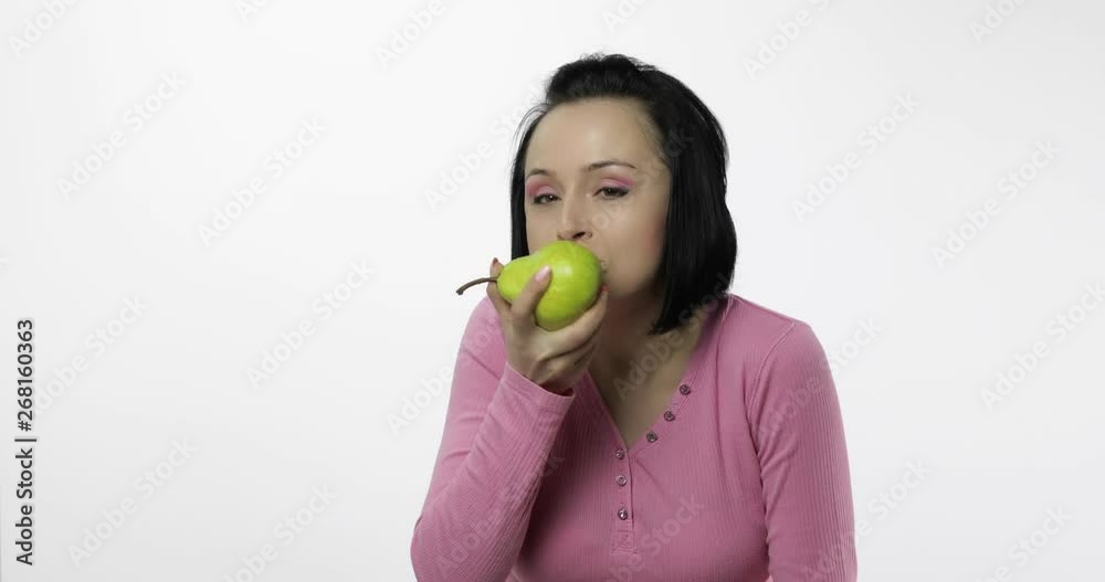 Young beautiful woman eating big, and juicy green pear on white background Young beautiful woman eating big, and juicy green pear on white background