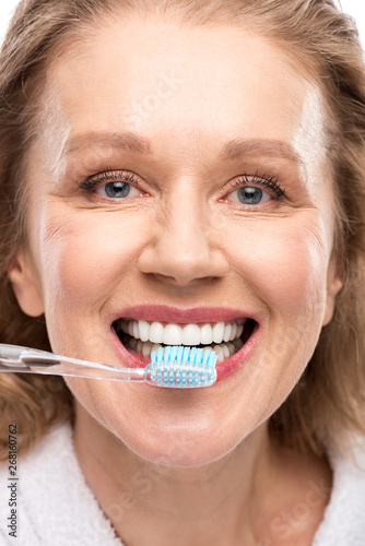 middle aged woman with toothy smile brushing Teeth Isolated On White