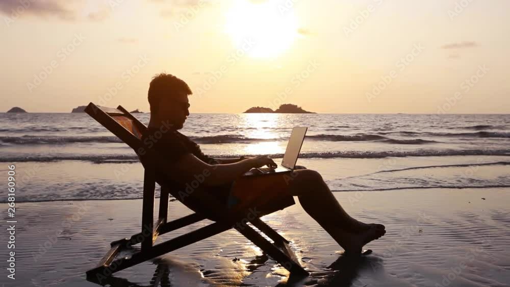 happy freelancer with laptop computer working on the beach, freelance work concept, dream office job workplace