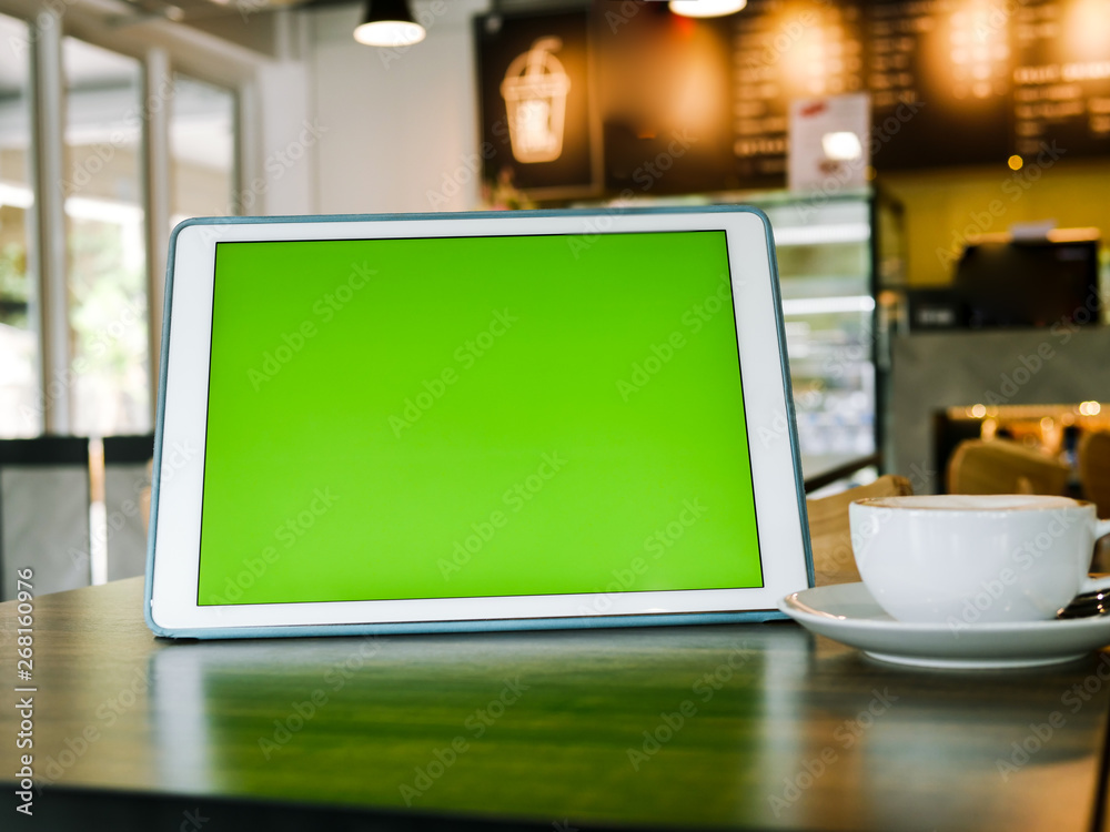 Fototapeta premium Green screen tablet and coffee mug on table, mock up.