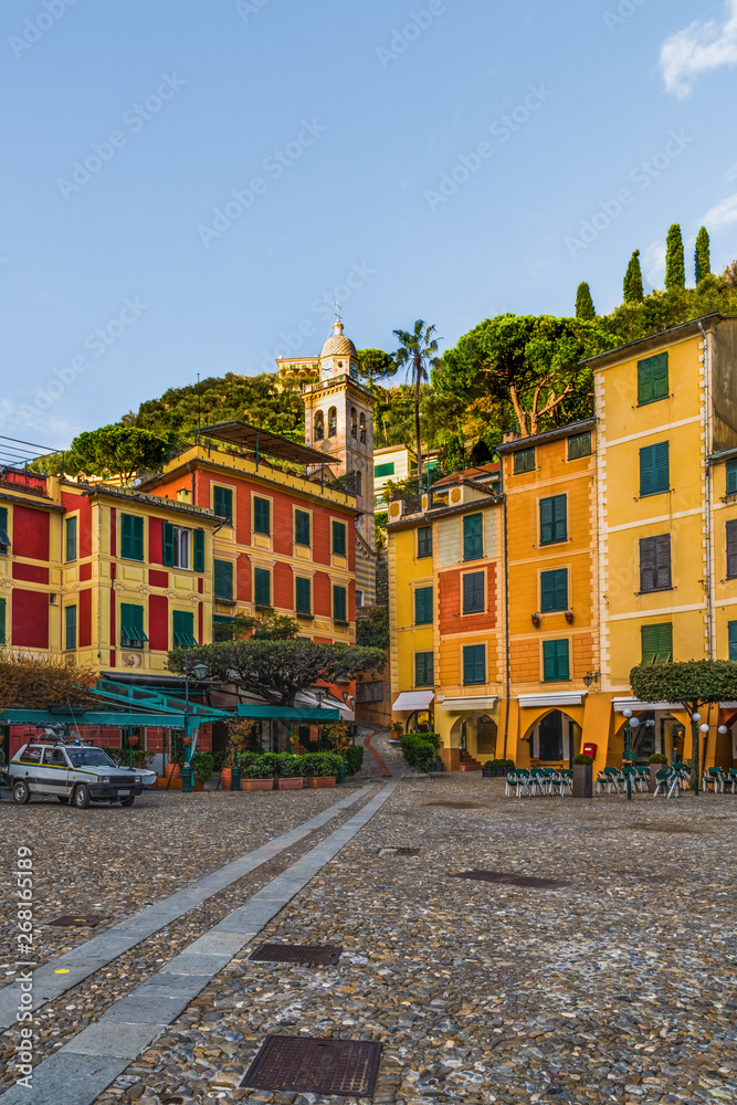 Obraz premium Colorful houses of the Piazzetta square and empty outdoor cafe in the coastal italian village Portofino in Liguria region, Italy