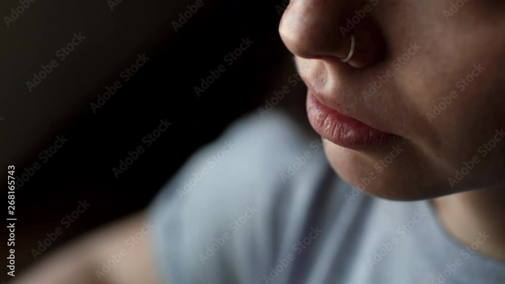 Girl with a ring in his nose is drinking coffee from a cup close-up in the cafe. Young woman enjoys a weekend or rest. Beautiful girl takes a sip of hot drink close-up