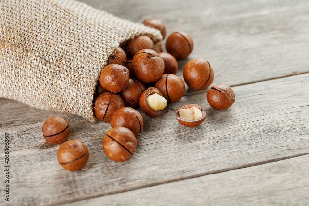 Macadamia nut on a wooden table in a bag, closeup, top view Macadamia nut on a wooden table in a bag, closeup, top view