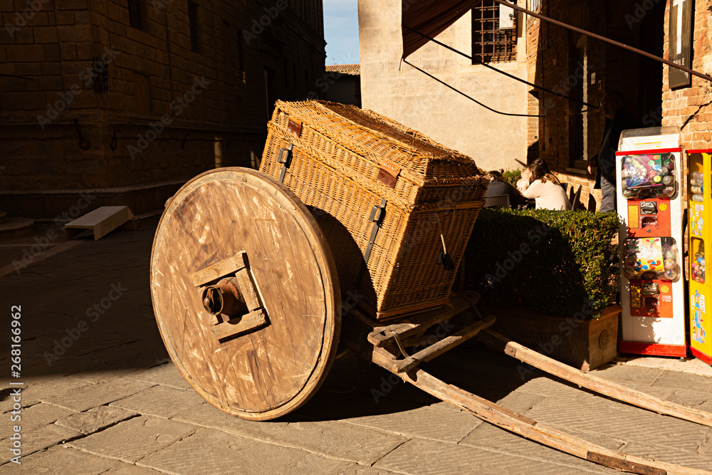 Carro antiguo de madera transportando baúl de mimbre.