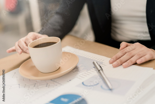 Close up business woman working and seeing graph on paper with a cup of coffee.