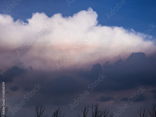 Clouds of thunder on the blue sky, backlit by the sun.