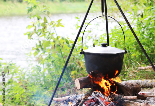 cooking delicious tasty food outdoors on fire an iron pot in summer in good weather with wood from the forest