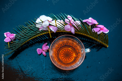 Detoxifying rosemary tea in a transparent glass cup on wooden surface.
