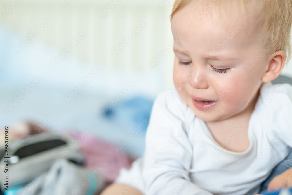 Cute caucasian blond toddler boy portrait crying at home during hysterics. Little child feeling sad. Little actor acting sadness emotions demanding something Cute caucasian blond toddler boy portrait crying at home during hysterics. Little child feeling sad. Little actor acting sadness emotions demanding something