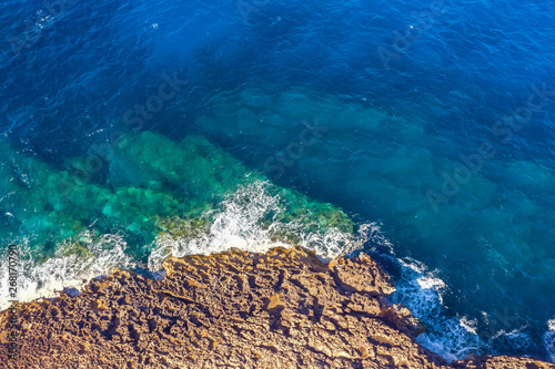 Sea coast on rocky beaches with turquoise water waves, aerial view. © aapsky