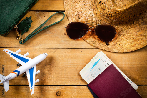 Composición de viaje junto a un avión, billetes aereos, pasaporte, gafas y sombrero sobre un fondo de madera rústico. Vista superior. Concepto: Viaje photo