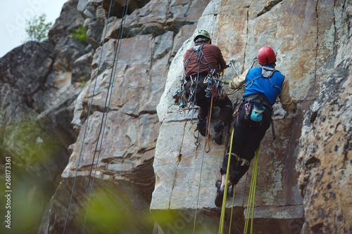 Two climbers work on the route entrenched on a rocky ledge. Climbing gear and equipment closeup.