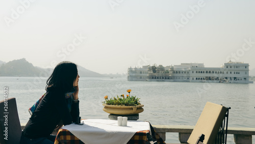 girl looks at Taj Lake Palace at Udaipur, India photo