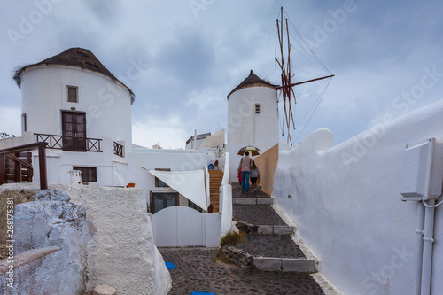 Tourists near windmill in the colorful village of Oia on a rainy day © Gianluca