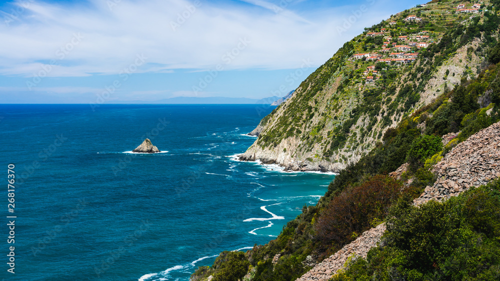 View over the stunning Tramonti coast, the Schiara village clinging to the mountain and a pyramid shaped rock named Scoglio Ferale in La Spezia, Italy.