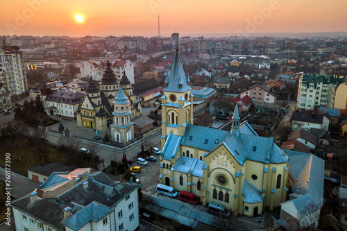 Aerial view of city at dawn or dusk. Urban landscape with church domes, parked cars, high buildings on bright pink sky at sunset background.