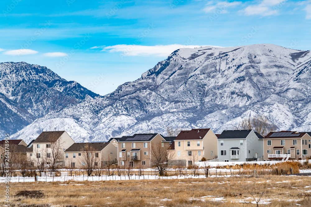 Row of beautiful homes against a rugged mountain dusted with snow in winter