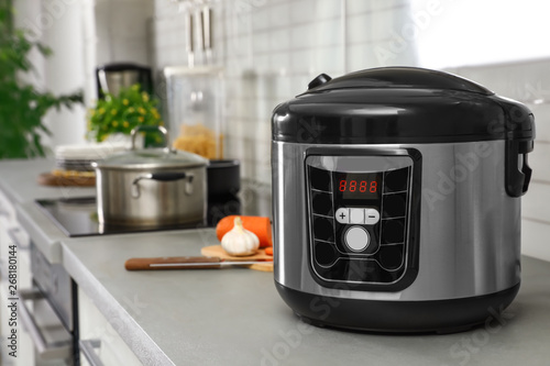Modern multi cooker on table in kitchen. Space for text