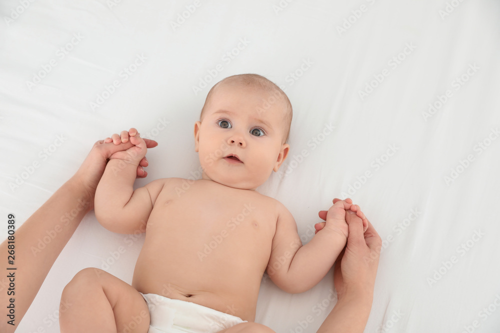 Mother and her cute child on white bed, top view. Baby massage and exercises Mother and her cute child on white bed, top view. Baby massage and exercises