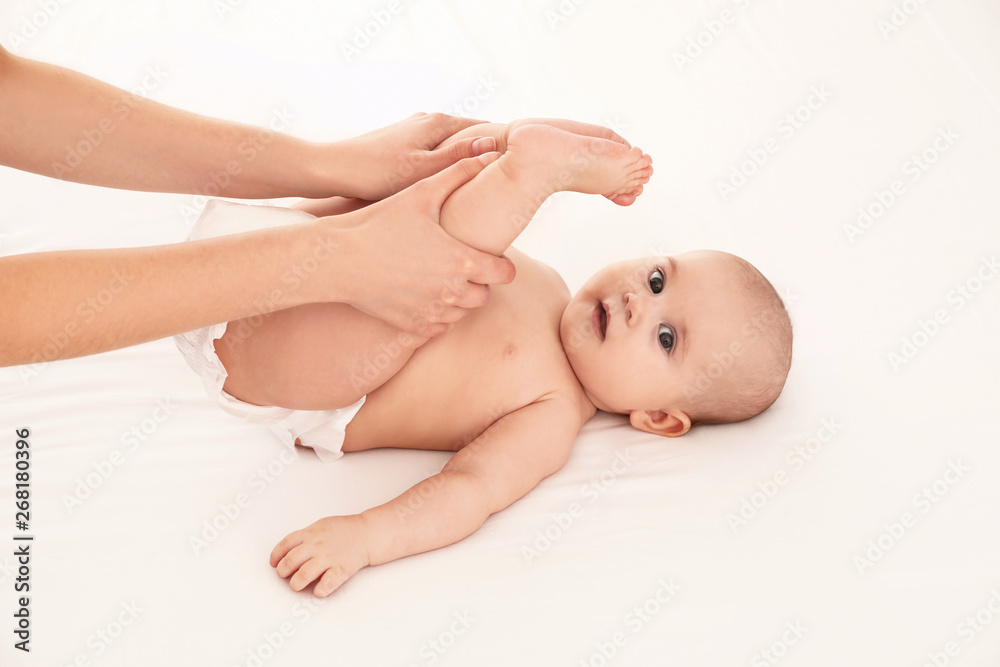 Mother and her cute child on white bed. Baby massage and exercises Mother and her cute child on white bed. Baby massage and exercises