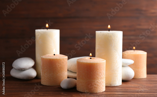 Composition of burning candles and spa stones on table