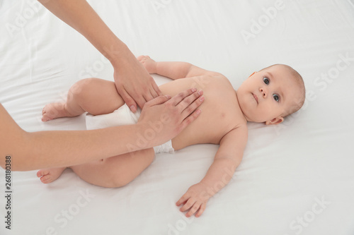 Mother and her cute child on white bed, above view. Baby massage and exercises