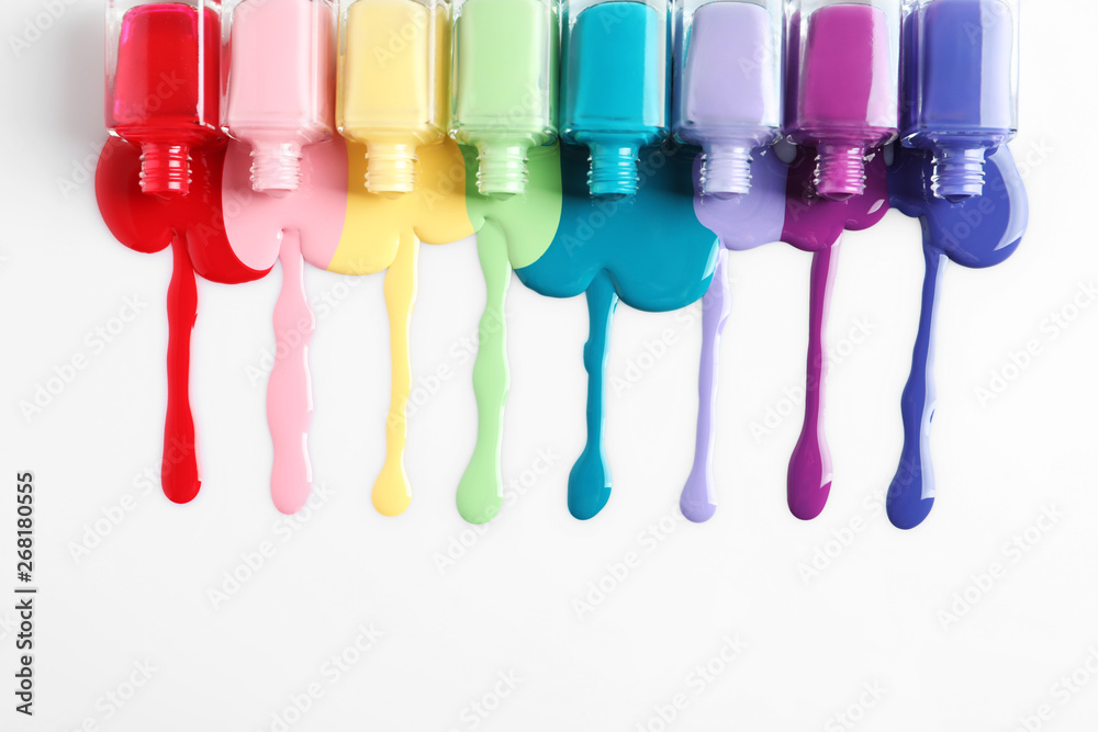 Spilled colorful nail polishes and bottles on white background, top view - obrazy, fototapety, plakaty 