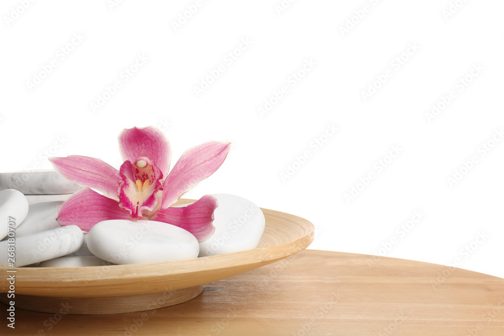 Wooden plate with orchid flower and spa rocks on table against white background. Space for text Wooden plate with orchid flower and spa rocks on table against white background. Space for text