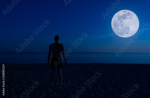 Shirtless man on the beach at night