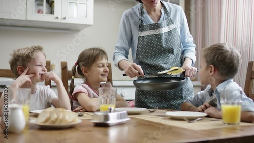 mom puts an omelet on her kids at a family dinner