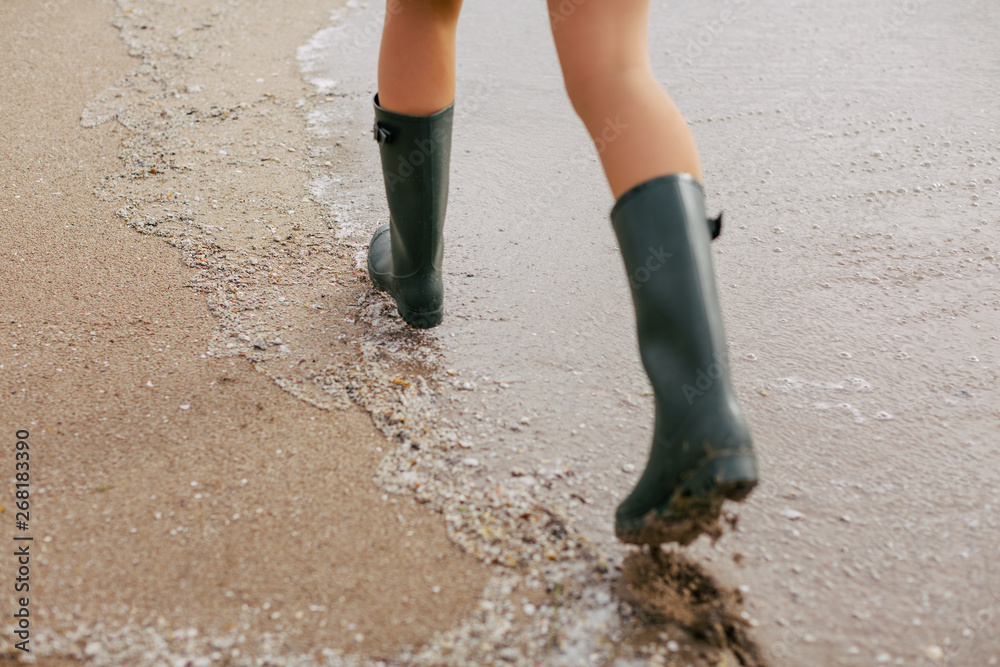 Closeup of a woman wearing gumboots walking on the beach. Closeup of a woman wearing gumboots walking on the beach.