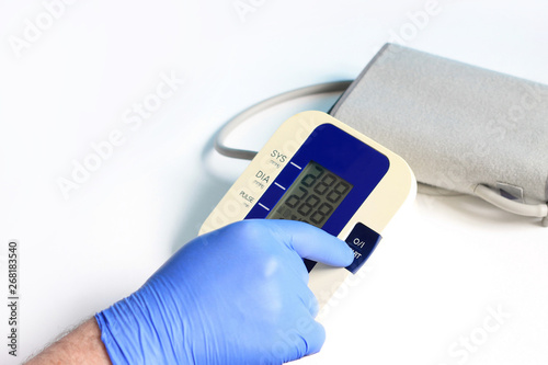 Male hands wear glove press start button on blood-pressure meter on white background.