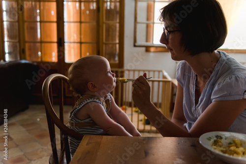 Mom giving food to baby on warm summer afternoon photo
