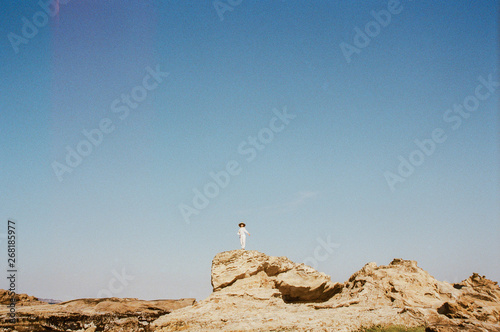 Young woman stand on rock formation in distance photo