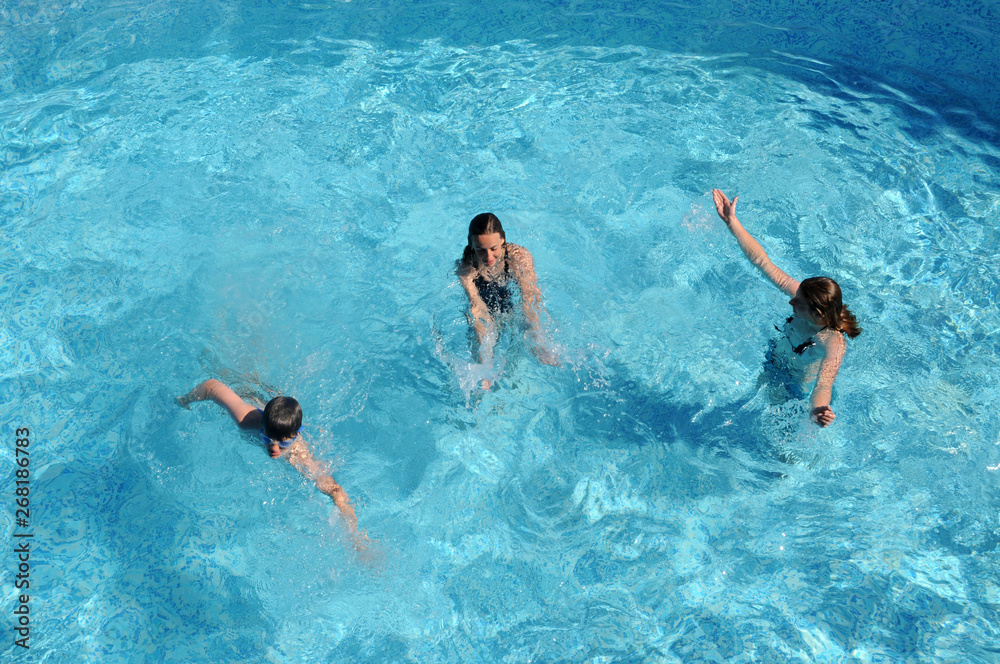 Three kids playing in swimming pool on holiday