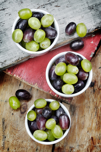 Three bowls filled with red and green grapes