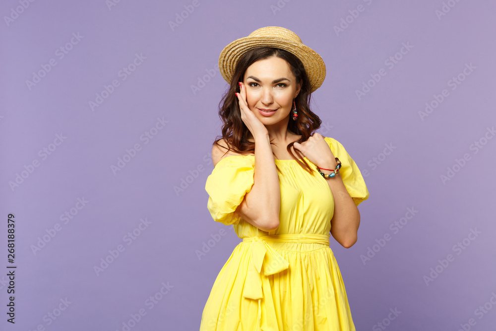 Attractive young woman in yellow dress summer hat looking camera, putting hand on cheek isolated on pastel violet background in studio. People sincere emotions, lifestyle concept. Mock up copy space. Attractive young woman in yellow dress summer hat looking camera, putting hand on cheek isolated on pastel violet background in studio. People sincere emotions, lifestyle concept. Mock up copy space.
