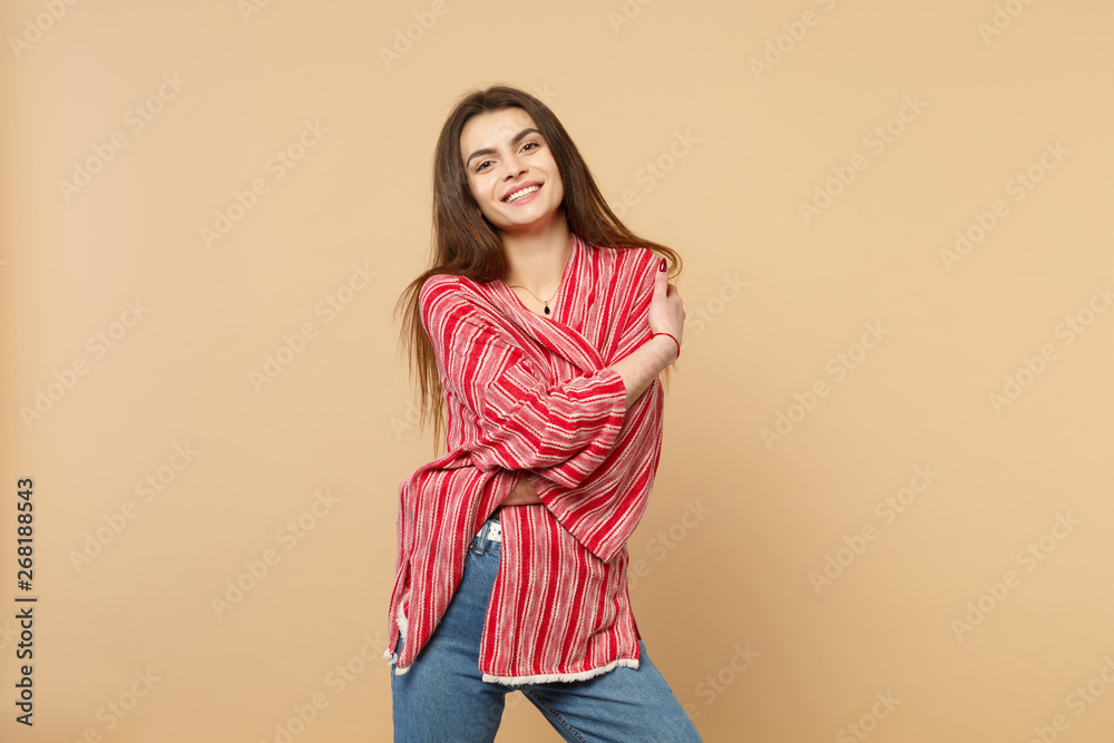 Portrait of smiling charming young woman in casual clothes standing, looking camera isolated on pastel beige wall background in studio. People sincere emotions lifestyle concept. Mock up copy space. Portrait of smiling charming young woman in casual clothes standing, looking camera isolated on pastel beige wall background in studio. People sincere emotions lifestyle concept. Mock up copy space.