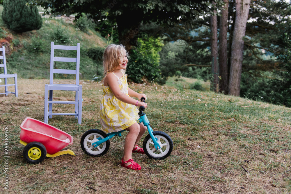 little girl playing with bike in the yard little girl playing with bike in the yard