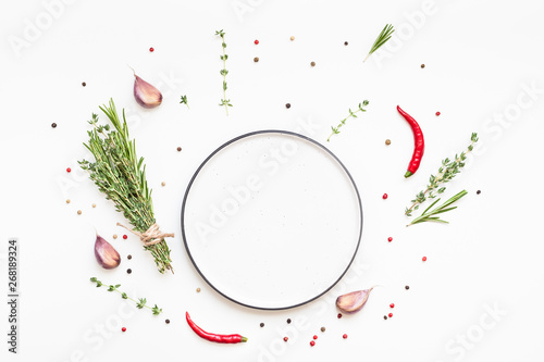 Fototapeta Naklejka Na Ścianę i Meble -  Empty plate with greens herbs and spices around