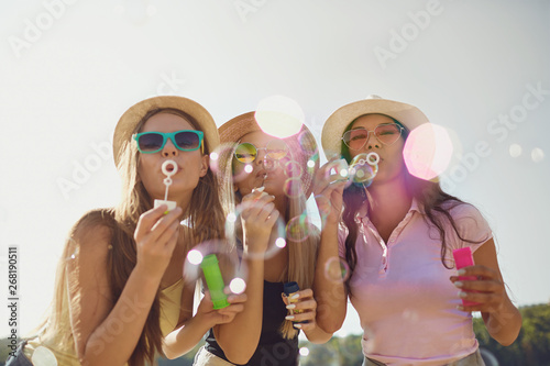 Quadro em tela Girlfriends  blowing soap bubbles on the beach.
