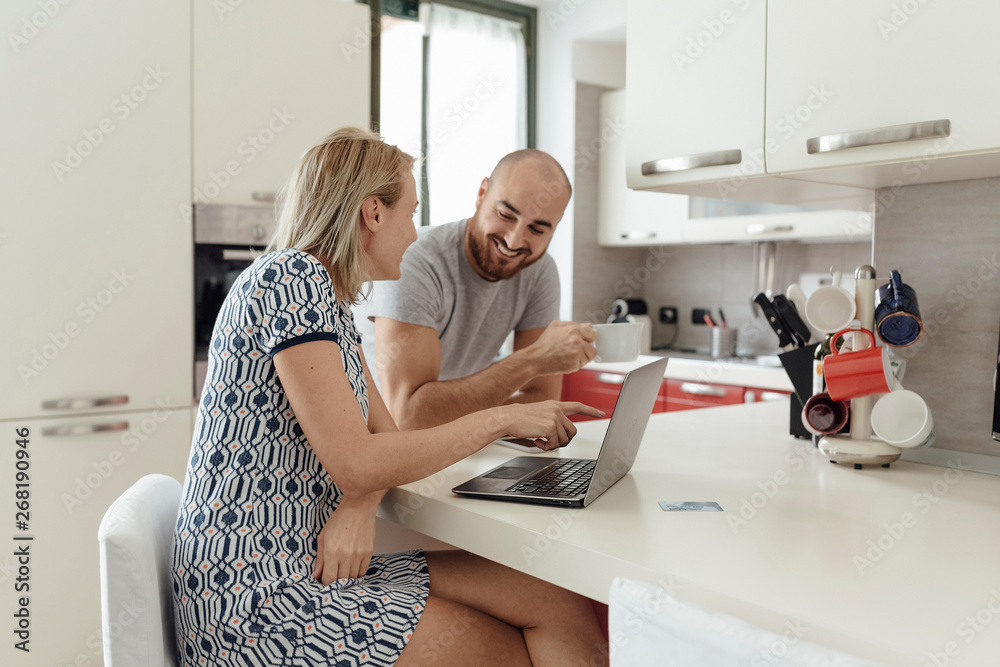 Adult Couple Using a Laptop From a Kitchen during the Morning Breakfast Adult Couple Using a Laptop From a Kitchen during the Morning Breakfast