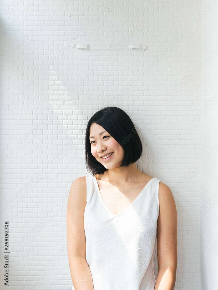 Minimalist portrait of joyful asian female with white background and sunlight Minimalist portrait of joyful asian female with white background and sunlight