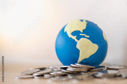 Global Business, Money, Finance and saving concept. Close up of mini world ball on pile of silver coins.