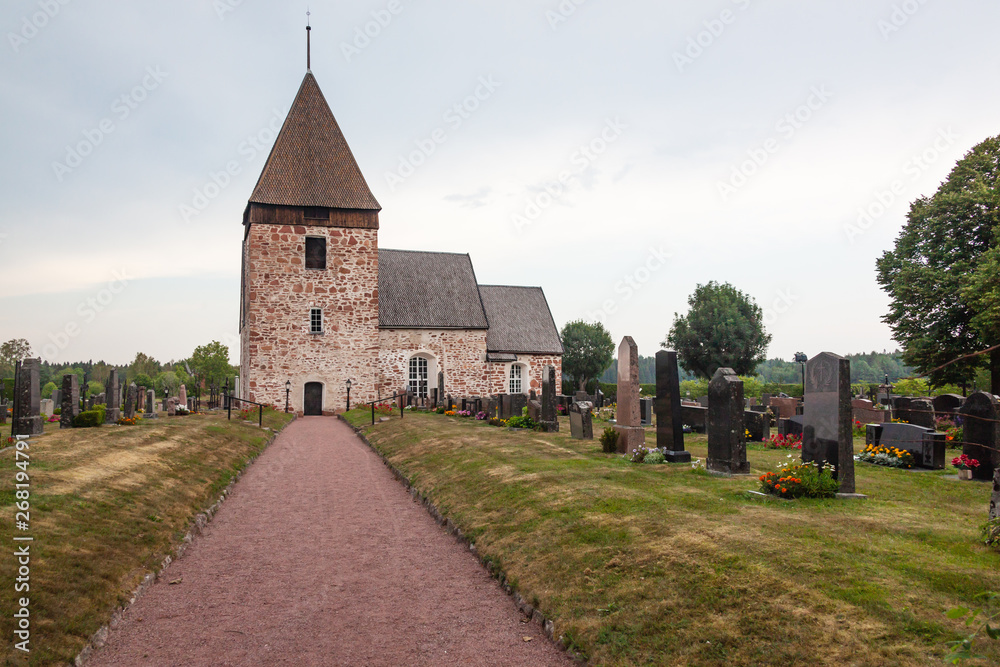 The old stone church martyr Saint Lawrence and the scenic cemetery on the hill in the Eckero, Aland islands, Finland