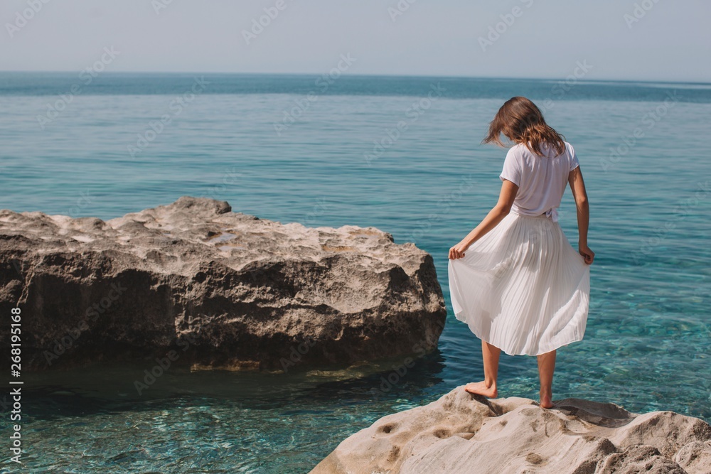 Back view portrait of unrecognizable brunette in white clothes near the sea Back view portrait of unrecognizable brunette in white clothes near the sea