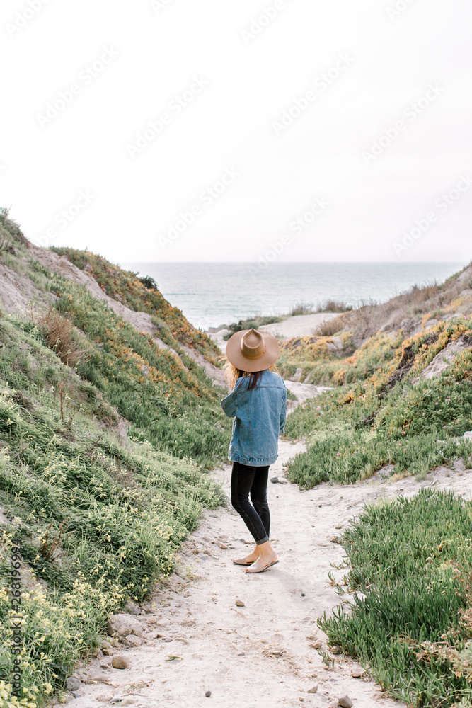 Stylish woman standing on pathway to beach Stylish woman standing on pathway to beach