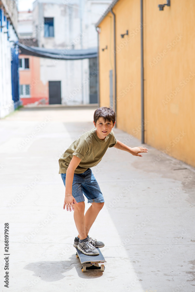 Front view of a cheerful skater boy riding on the street in a sunny day Front view of a cheerful skater boy riding on the street in a sunny day