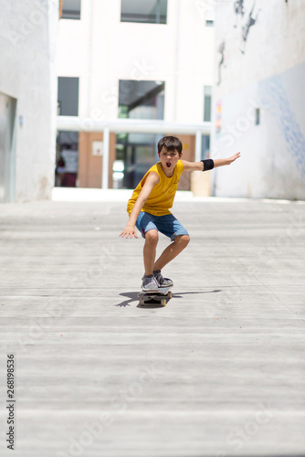 Front view of cheerful skater boy riding on the city in a sunny day